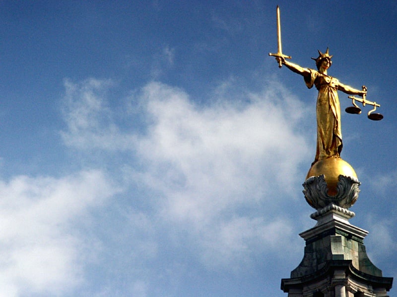 The Old Bailey's golden statue of justice see against a cloudy blue sky