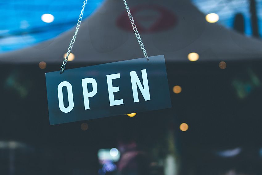 An 'open' sign hanging in a shop's glass door